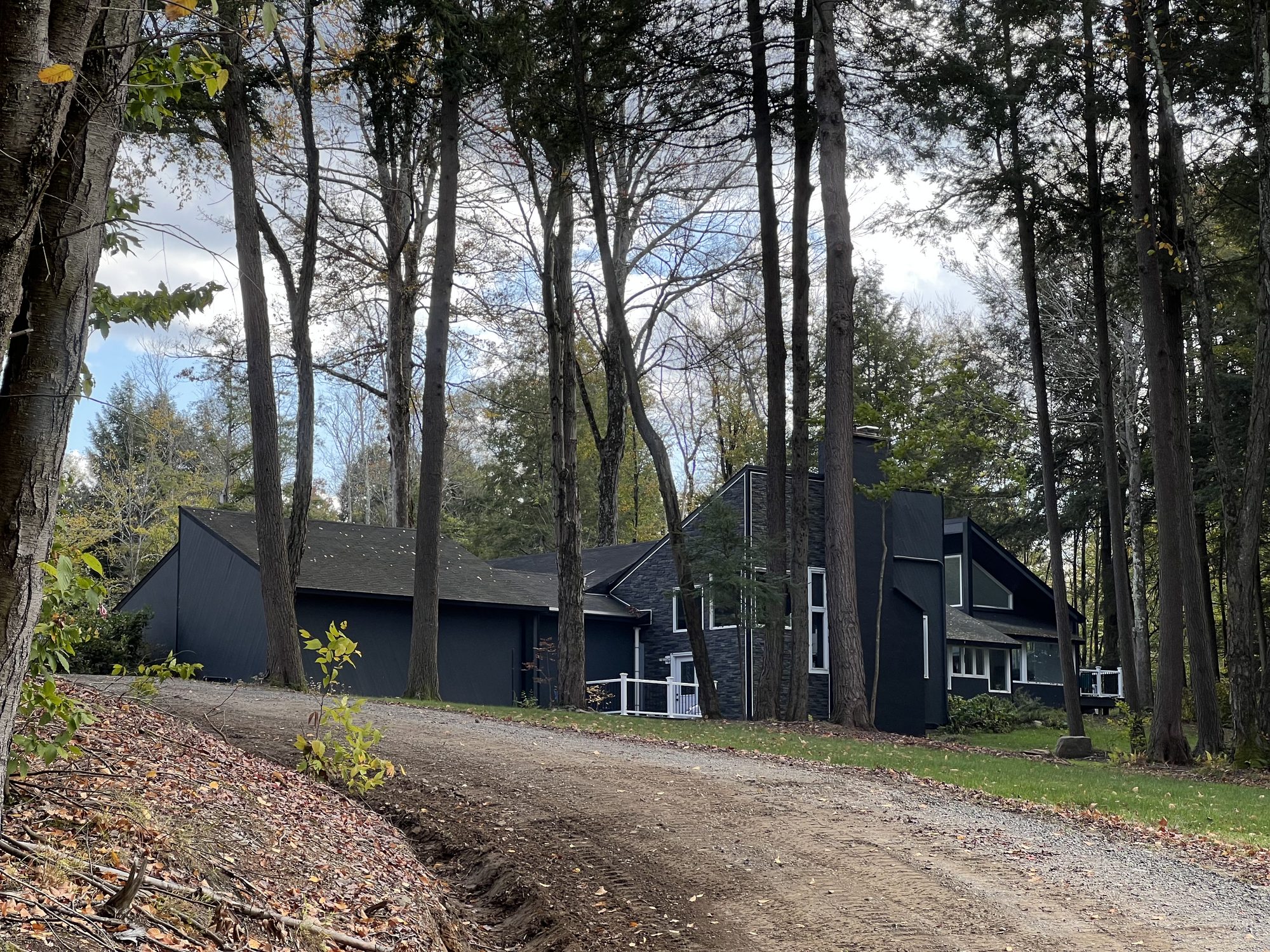 A gravel driveway running up to a dark-sided house